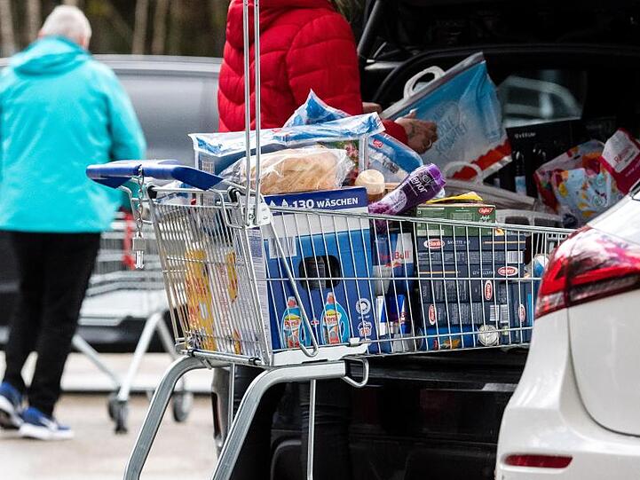 Ein Kunde lädt seine Einkäufe aus einem bis zum Rand gefüllten Einkaufswagen in den Kofferraum seines Fahrzeugs. Foto: Matthias Balk/dpa/Archivbild