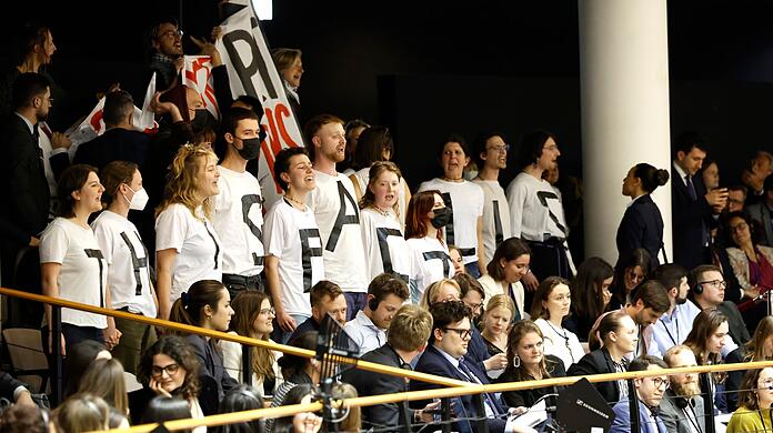 Aktivisten protestieren von der Besuchertribüne aus.