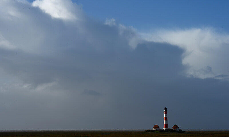 Wolken ziehen am Donnerstag über die Nordsee und den Leuchtturm von Westerhever (Schleswig-Holstein).