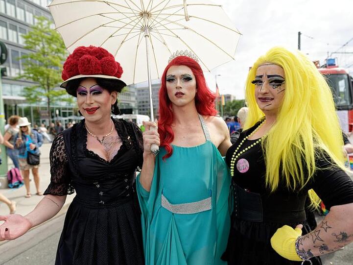 Die Dragqueens Betty BBQ (l) und Lilly Lips (r) posieren mit einer Prinzessin.