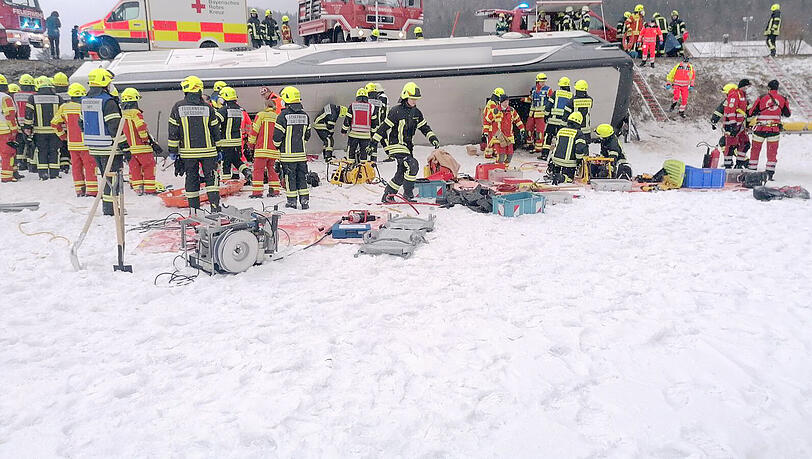 Einsatzkräfte der Feuerwehr an der Unfallstelle mit dem umgekippten Reisebus.
