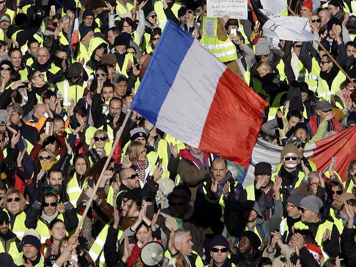 Demonstranten der "Gelbwesten" schwenken französische Fahnen während eines Protestzugs durch Marseille.