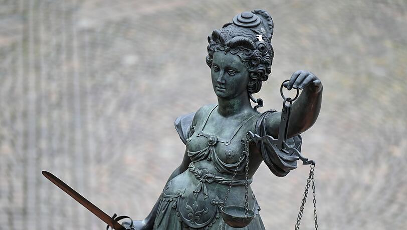Eine Statue der Justitia hält eine Waage und ein Schwert in der Hand.
