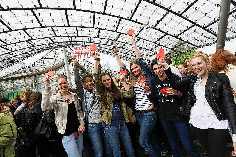"One Direction" spielen am Freitag in der Olympiahalle. Jubelnde Fans warten im Regen vor der Olympiahalle.
