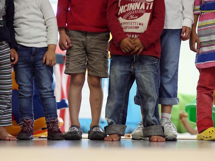 Kinder stehen in einem Kindergarten nebeneinander.