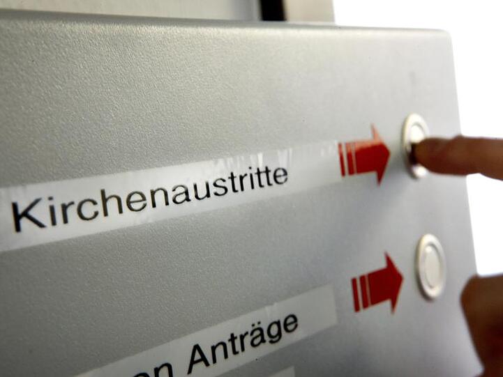 Eine Wartenummer für den Antrag auf den Austritt aus der Kirche drückt eine Frau beim Amtsgericht Köln.