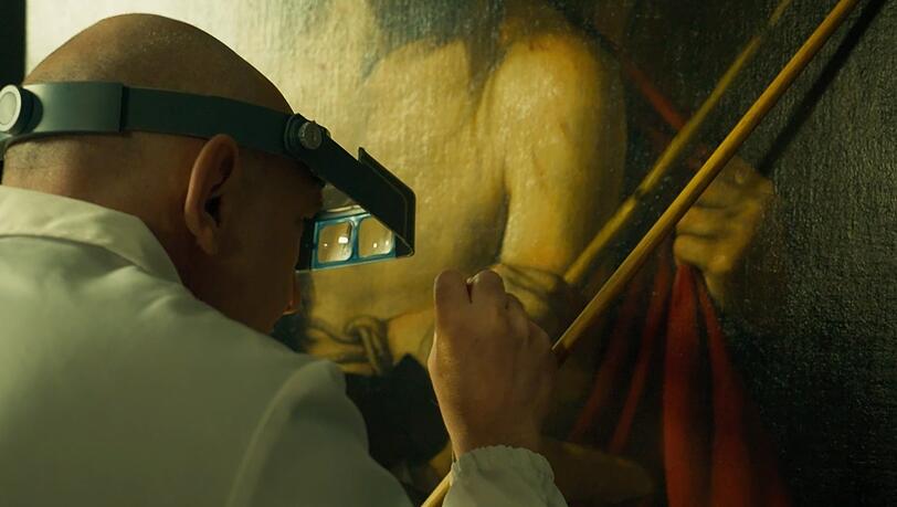 Vergilbte Firnis und Schmutz haben Caravaggios „Ecce Homo“ quasi einen Deckmantel verpasst. Hier ist ein Restaurator dabei, das Bild von diesen Überlagerungen zu befreien. Vergilbte Firnis und Schmutz haben Caravaggios „Ecce Homo“ quasi einen Deckmantel verpasst. Hier ist ein Restaurator dabei, das Bild von diesen Überlagerungen zu befreien.