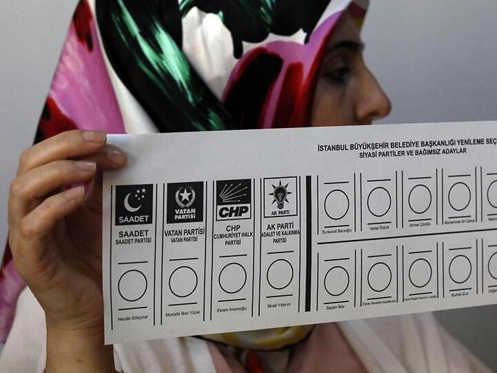 Eine Wahlhelferin hält in einem Wahllokal in Istanbul einen Stimmzettel in der Hand.