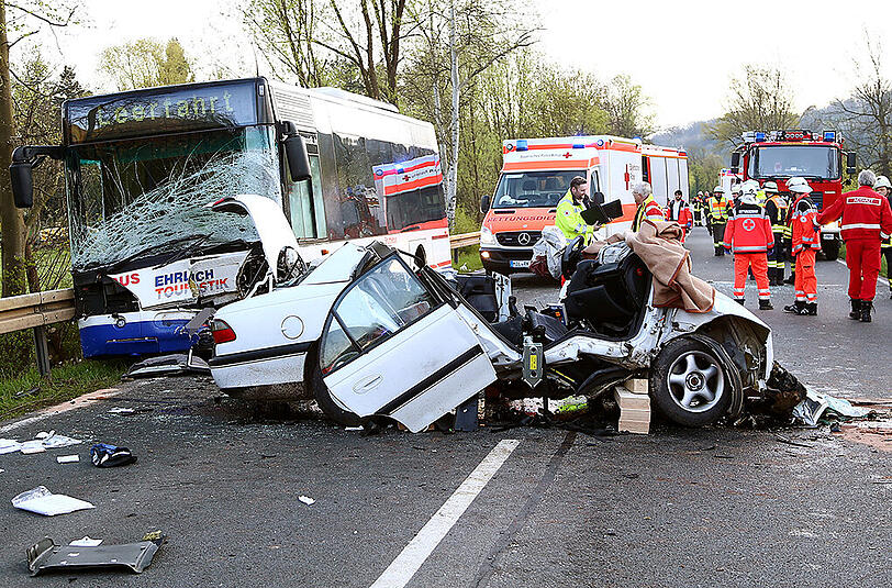 Rettungskräfte stehen am Dienstagmorgen an einer Unfallstelle bei Weilbach (Bayern). Bei dem Zusammenstoß zwischen einem Auto und einem Linienbus auf einer Bundesstraße in Unterfranken ist der Autofahrer getötet worden. Foto: Ralf Hettler