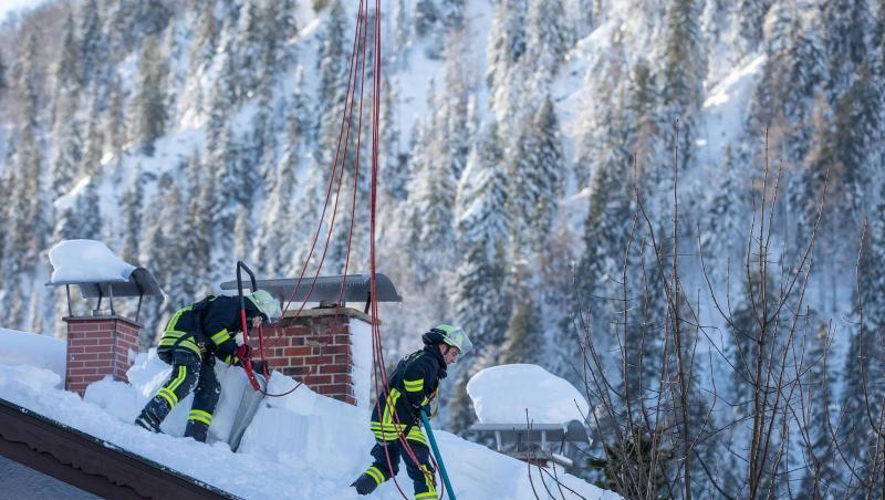 Feuerwehrleute räumen auf einem Haus in Bayrischzell im Grenzgebiet zu Österreich Schnee von einem Dach. Foto: Christoph Reichwein Feuerwehrleute räumen auf einem Haus in Bayrischzell im Grenzgebiet zu Österreich Schnee von einem Dach. Foto: Christoph Reichwein