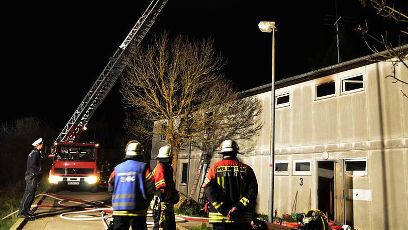 Einsatzkräfte von Feuerwehr und Polizei stehen in Weil der Stadt vor der Flüchtlingsunterkunft, in der das Feuer ausgebrochen war. Einsatzkräfte von Feuerwehr und Polizei stehen in Weil der Stadt vor der Flüchtlingsunterkunft, in der das Feuer ausgebrochen war.