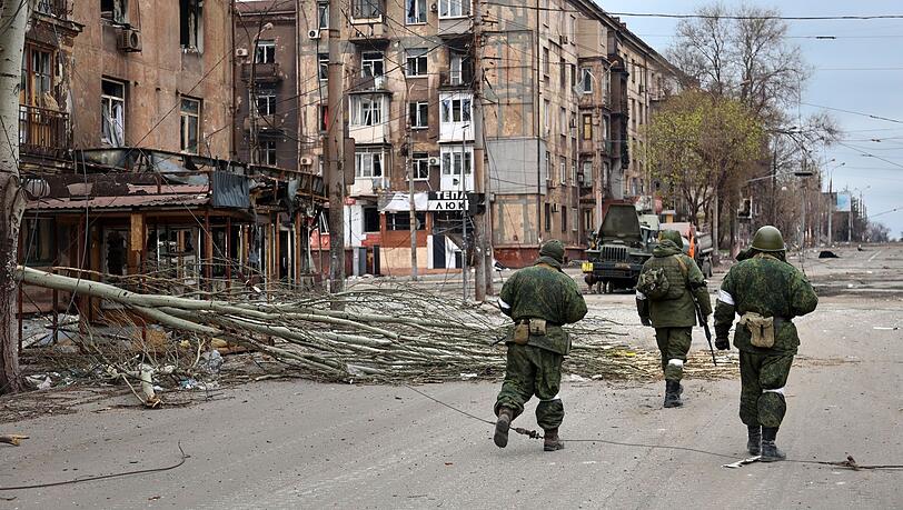 Soldaten der Miliz der "Volksrepublik" Donezk gehen an beschädigten Wohnhäusern in Mariupol vorbei.