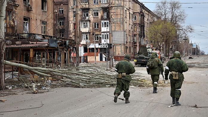 Soldaten der Miliz der "Volksrepublik" Donezk gehen an beschädigten Wohnhäusern in Mariupol vorbei.