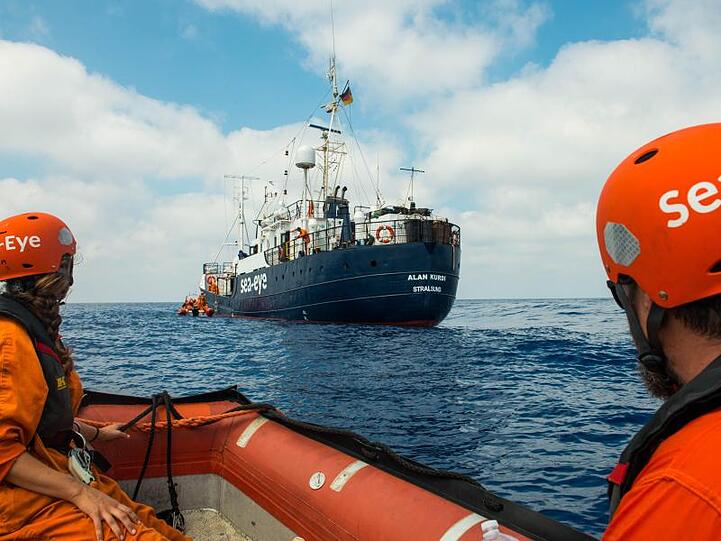 Zwei Seenotretter vor dem Rettungsschiff "Alan Kurdi".
