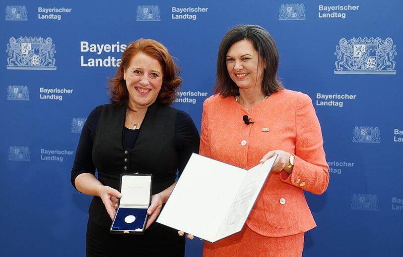 Luise Kinseher (l), Kabarettistin aus Deutschland, erhält von Ilse Aigner (CSU), Landtagspräsidentin, im Bayerischen Landtag die Verfassungsmedaille.