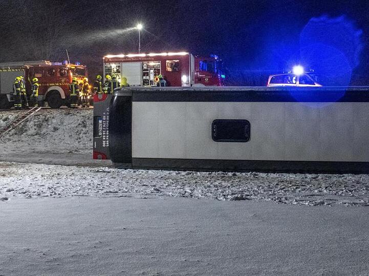 Ein Reisebus liegt umgestürzt neben der B10 bei Tomerdingen nördlich von Ulm in einem Feld. Bei schneeglatter Fahrbahn und starkem Wind kam der Bus von der Straße ab.