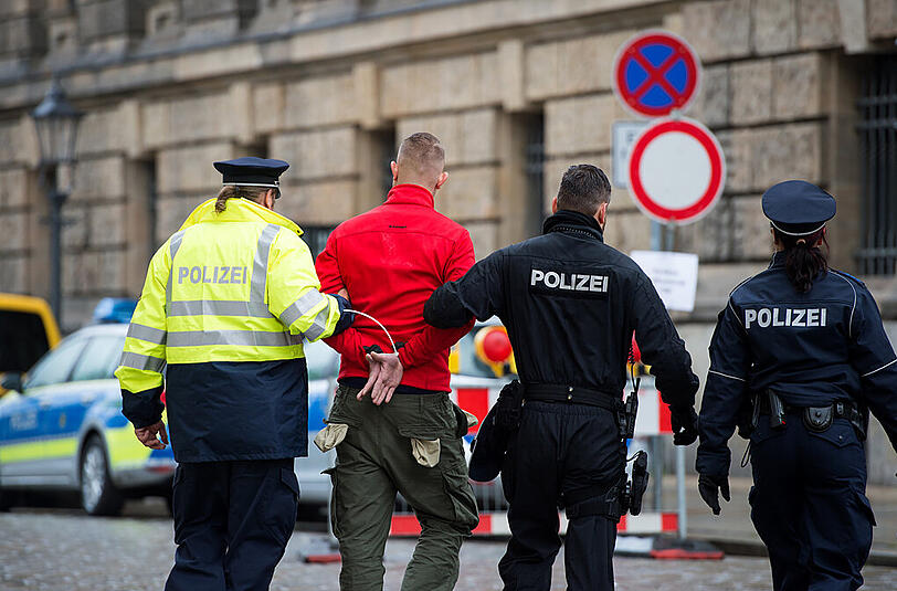 Polizisten führen einen Demonstranten ab.