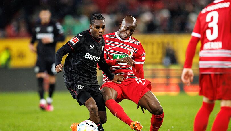 Jeremie Frimpong von Bayer Leverkusen (l) und Kelvin Yeboah vom FC Augsburg im Zweikampf um den Ball.