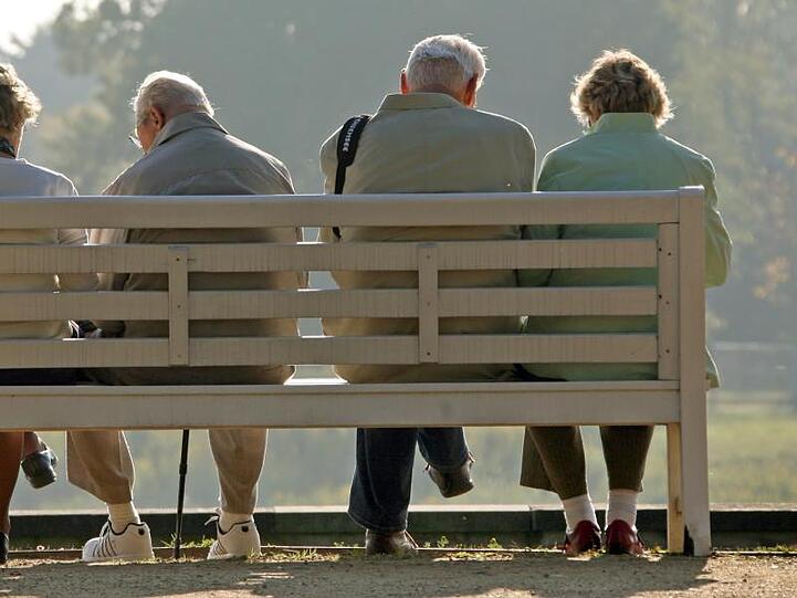 Rentner sitzen auf einer Parkbank.