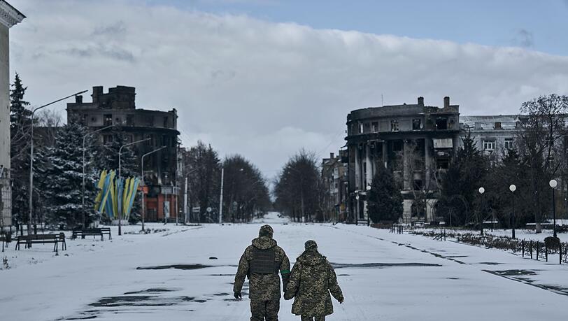 Ein ukrainischer Soldat und eine Soldatin gehen händchenhaltend durch Bachmut. In der schwer umkämpften Stadt im Osten des Landes geraten die ukrainischen Streitkräfte immer stärker unter Druck.