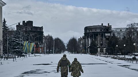 Ein ukrainischer Soldat und eine Soldatin gehen händchenhaltend durch Bachmut. In der schwer umkämpften Stadt im Osten des Landes geraten die ukrainischen Streitkräfte immer stärker unter Druck.