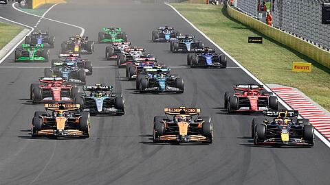 Max Verstappen (r.), Lando Norris (m.) und Oscar Piastri biegen praktisch gleichauf in die erste Kurve ein.