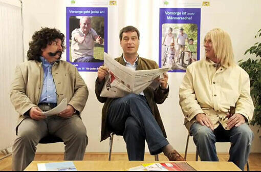 Ein Bild aus dem Spot zur Aktion: Markus Söder zwischen den kostümierten Waldi Hartmann (l.) und Schauspieler Wolfgang Fierek.