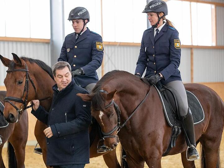 Markus Söder (CSU), Ministerpräsident von Bayern, steht neben den Polizeireitern Robin Philipp mit Pferd Hermes und Stephanie Sendker mit Pferd Noris bei der Vorstellung der neuen Reitergruppe der mittelfränkischen Polizei. Foto: Daniel Karmann