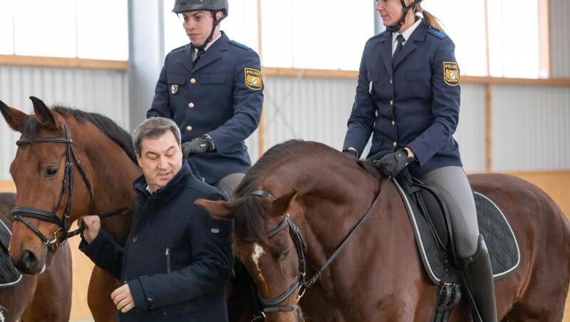Markus Söder (CSU), Ministerpräsident von Bayern, steht neben den Polizeireitern Robin Philipp mit Pferd Hermes und Stephanie Sendker mit Pferd Noris bei der Vorstellung der neuen Reitergruppe der mittelfränkischen Polizei. Foto: Daniel Karmann
