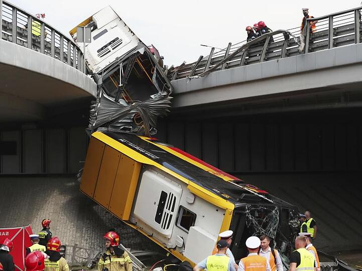 Einsatzkräfte arbeiten an der Unfallstelle. Mindestens ein Mensch ist bei dem Absturz des Linienbusses ums Leben gekommen.