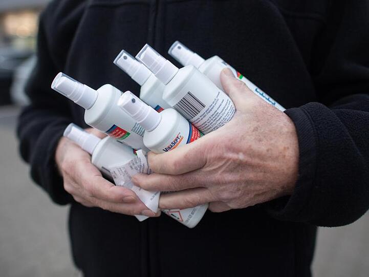 Ein Kunde mit sechs Einheiten Desinfektionsmittel verlässt am frühen Morgen einen Aldi-Markt.