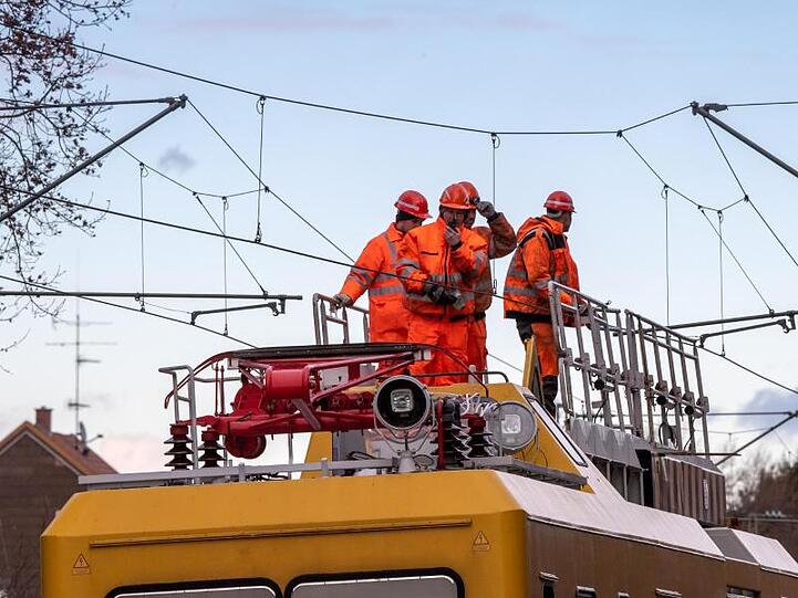 Bahnarbeiter auf Turmtriebwagen bei Arbeit an Oberleitung. Foto: Peter Kneffel/dpa