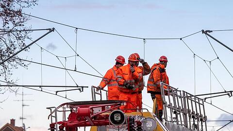 Bahnarbeiter auf Turmtriebwagen bei Arbeit an Oberleitung. Foto: Peter Kneffel/dpa