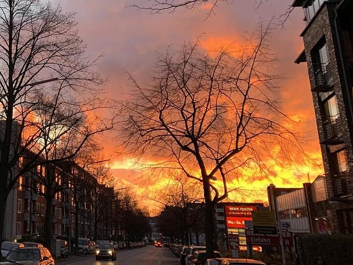 Im Stadteil Winterhude entsteht bei einem Sonnenuntergang durch das sich in den Wolken brechende Licht der Eindruck eines Großfeuers.