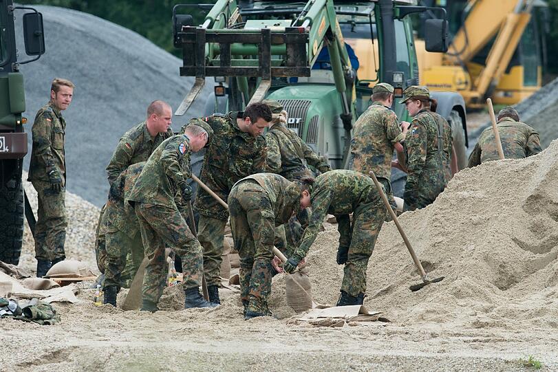 Bundeswehrsoldaten helfen den Damm abzudichten.