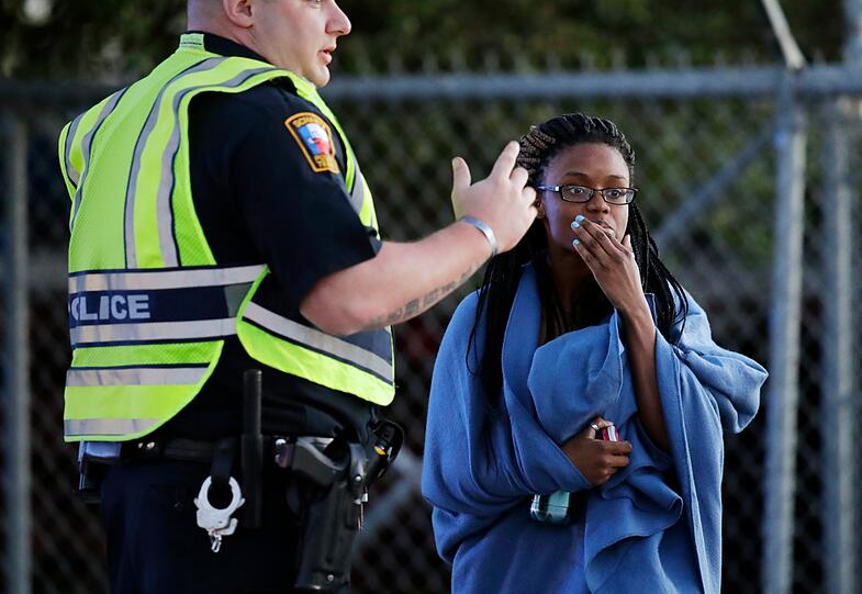 Eine in eine Decke gewickelte Mitarbeiterin des Transportdienstes FedEx spricht mit einem Polizisten. In dem Unternehmen in dem Ort Schertz in der Nähe der Großstadt San Antonio ist in eine mittelgroße Kiste explodiert. Im US-Staat Texas gab es die mittlerweile fünfte Paket-Explosion in diesem Monat.