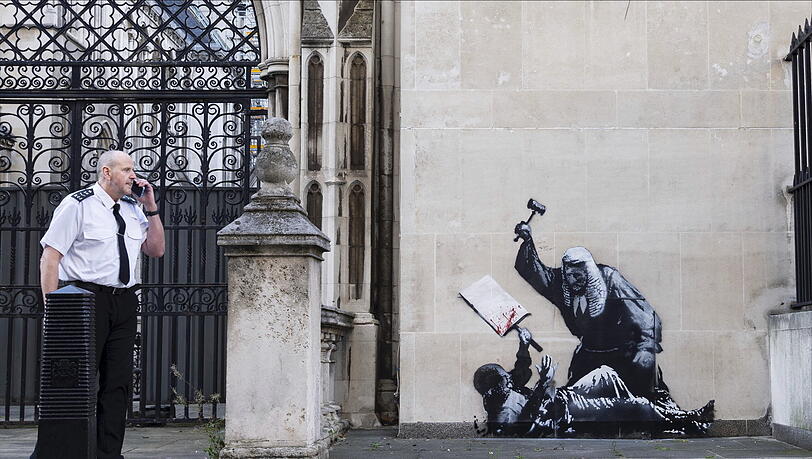 Ein undatiertes, von Banksy veröffentlichtes Foto des neuen Kunstwerks des Künstlers, das einen Richter zeigt, der einen Demonstranten mit einem Hammer vor den Royal Courts of Justice in London schlägt. Ein undatiertes, von Banksy veröffentlichtes Foto des neuen Kunstwerks des Künstlers, das einen Richter zeigt, der einen Demonstranten mit einem Hammer vor den Royal Courts of Justice in London schlägt.