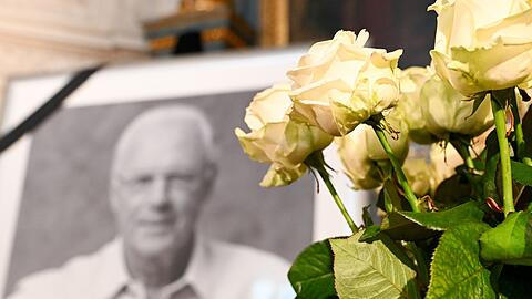 Ein Porträt von Franz Beckenbauer ist neben weißen Rosen in der Hofkapelle der Residenz zu sehen.
