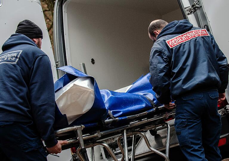 Mitarbeiter der Gerichtsmedizin bringen in einem Waldstück an der Bärenlauchstraße eine Leiche zu ihrem Fahrzeug.