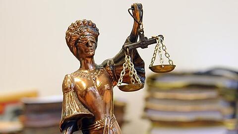 Eine goldfarbene Justitia-Figur steht vor Aktenbergen. Foto: Britta Pedersen/dpa-Zentralbild/dpa/Archivbild