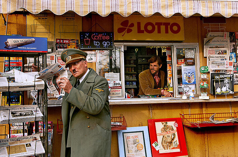 Er ist wieder da: &bdquo;Der Führer&ldquo; (Oliver Masucci) taucht vor einem Kiosk (Kioskbesitzer: Lars Rudolph) im heutigen multikulturellen Berlin auf.