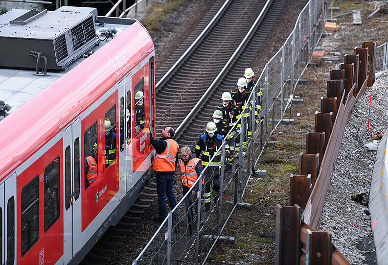 Einsatzkräfte der Feuerwehr gehen am Einsatzort zu einer S-Bahn.