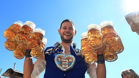 Eine Bedienung bringt Ma&szlig;kr&uuml;ge mit Bier in das Hacker-Festzelt.