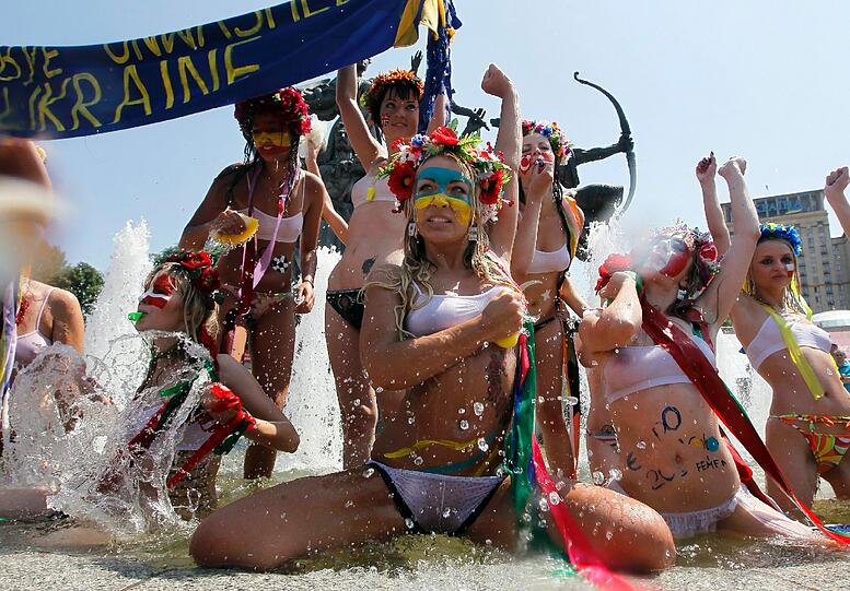 Als internationale Fußball-Fans verkleidet baden die Damen in einem Brunnen auf dem Unabhängikeits-Platz in Kiev.
