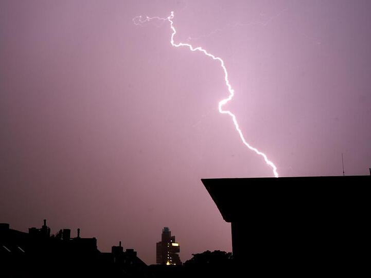 Blitze leuchten während eines Gewitters am Himmel. Foto: Julian Stratenschulte/Archivbild