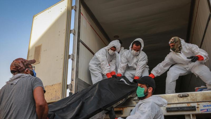 Arbeiter in Schutzkleidung beladen in Bagdad einen Kühlwagen mit Leichen von Menschen, die am Coronavirus gestorben sind. Arbeiter in Schutzkleidung beladen in Bagdad einen Kühlwagen mit Leichen von Menschen, die am Coronavirus gestorben sind.