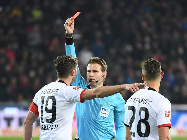 Schiedsrichter Felix Brych zeigt David Abraham nach einem Foul an Freiburgs Trainer Christian Streich die Rote Karte.