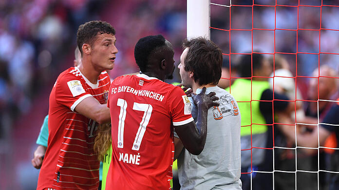 Benjamin Pavard  und Sadio Mané reden auf den Aktivisten ein.