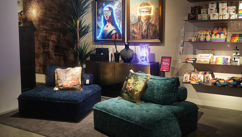 Farbige Sofaelemente vor dem Pride-Regal.