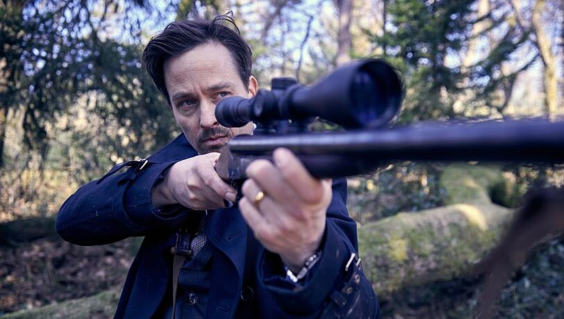 "Der Pfau": Andreas (Tom Schilling) hat ein Gewehr im Wald gefunden und richtet es auf seine Team-Mitglieder.